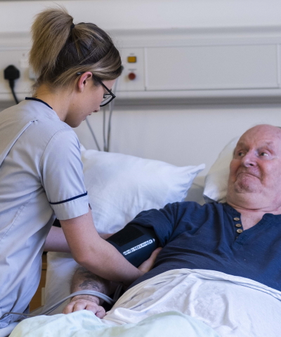 Nursing student taking a patient\&#039;s blood pressure on a hospital ward